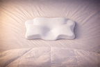 Oreiller NightRitual blanc installé sur un lit pour une ambiance de chambre sereine.